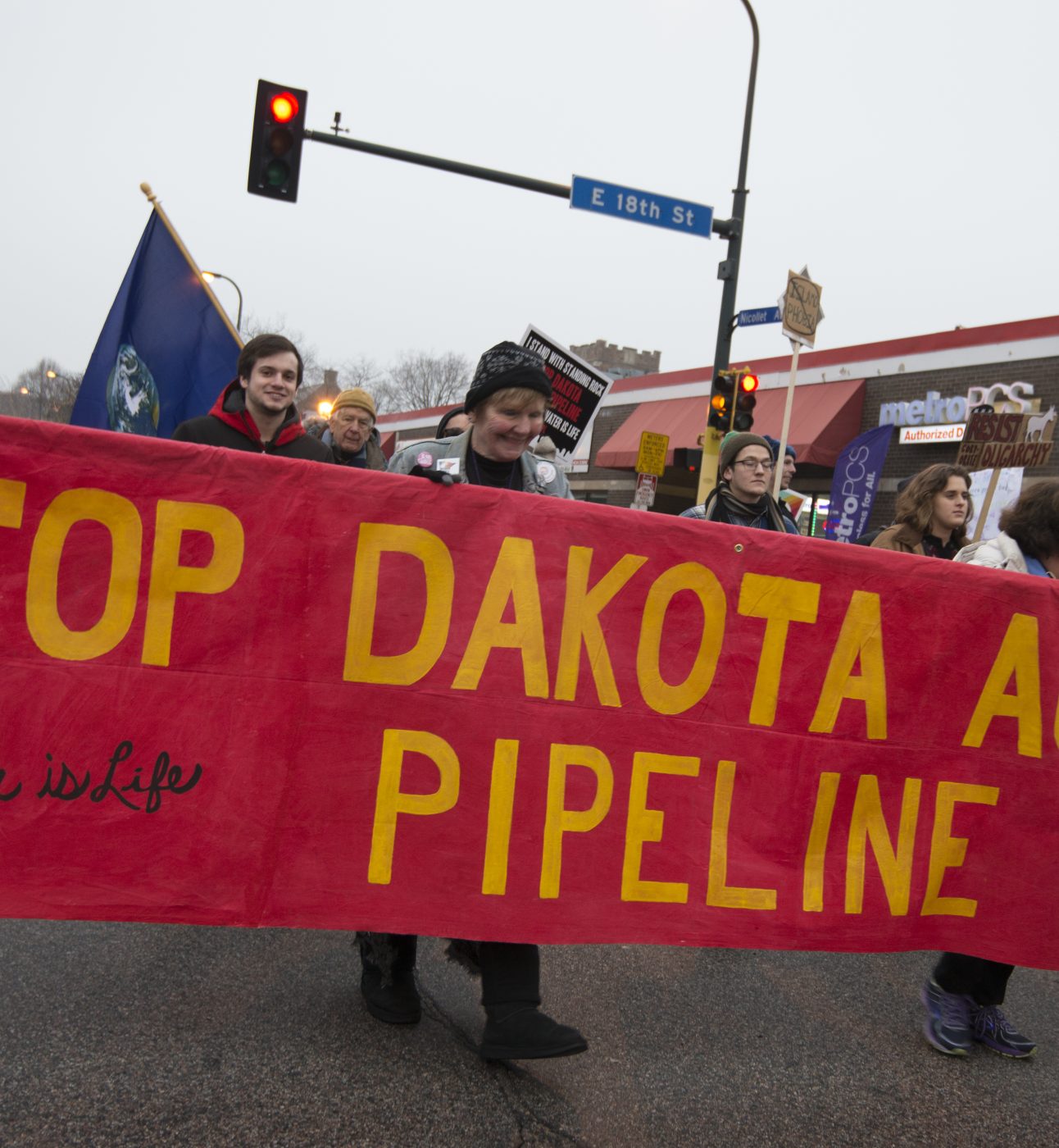 Activists holding a large red banner that reads, 