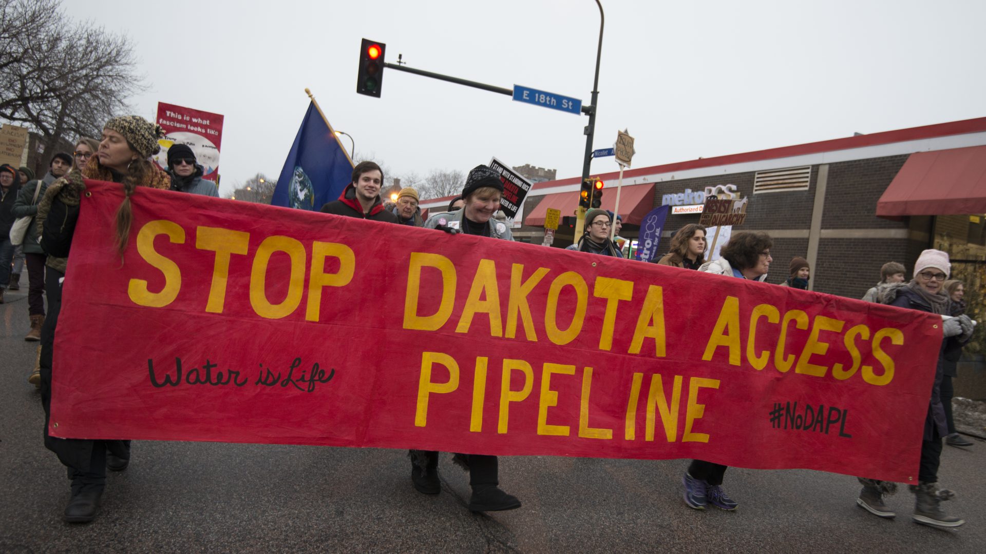 Activists holding a large red banner that reads, 