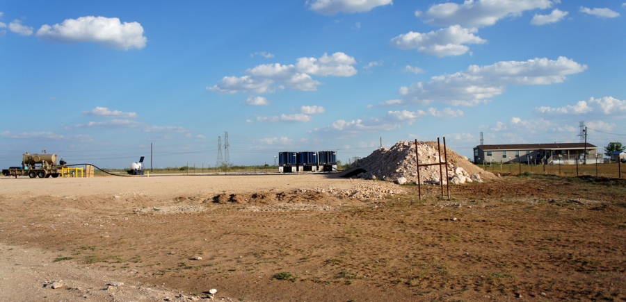 A wall of rubble stands between a Gardendale house and the yard where the homeowners once grazed animals. Now the yard is a drill pad with a fracked well. (Credit Anna Simonton) 