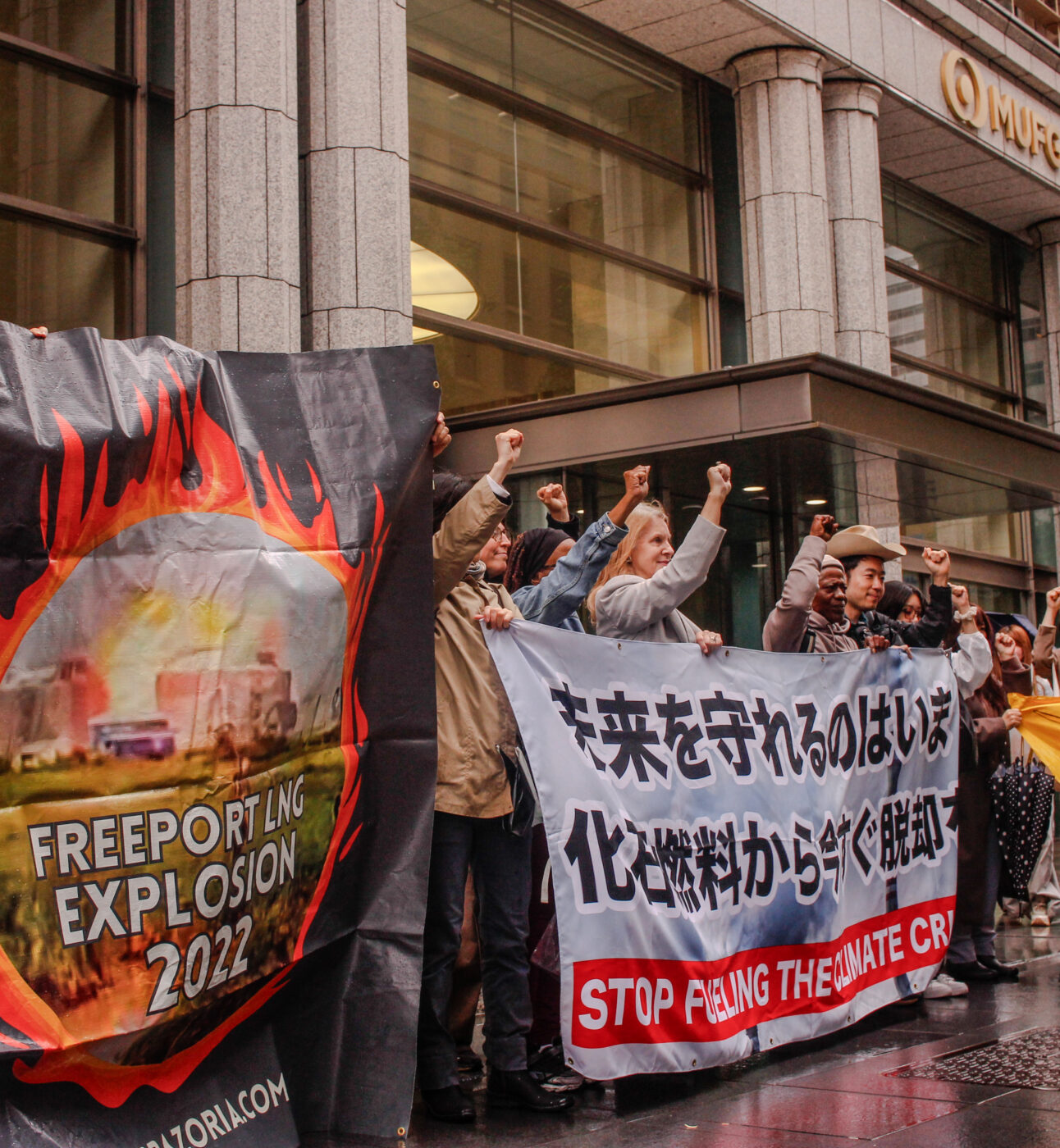 Activists hold signs protesting Japan's funding of fossil fuels.
